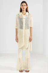 Camisa larga de punto abierto color crema, con cuello clásico, manga corta y cierre frontal con botones.