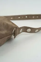 Bolso tipo shopper de gamuza marrón, con asa de hombro ajustable decorada con ojales metálicos plateados y hebilla lateral.