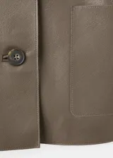Chaqueta Sabi de cuero sintético en color verde militar, con cuello camisero, cierre frontal con botones y bolsillos de parche delanteros.