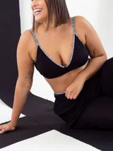 Soutien triángulo básico negro sin aro, confeccionado en algodón elastizado con breteles finos y contorno inferior con estampado floral.