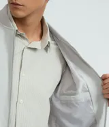 Campera estilo bomber de color negro, confeccionada con tejido repelente al agua. Posee cuello semi alto, cierre frontal con cremallera, bolsillos laterales y puños y dobladillo elastizados. Marca Marfinno.
