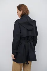 Trench coat negro de corte midi, con cuello solapa, cierre frontal cruzado con botones y cintas ajustables en los puños.