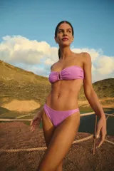 Conjunto de bikini violeta de lycra texturada simil toalla. El corpiño es strapless con tiras ajustables y unión de taza con avío metálico. La bombacha es vedetina con forrería a tono.