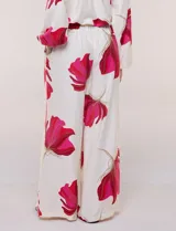 Conjunto de dos piezas de crep compuesto por una blusa holgada con escote en V y mangas largas abullonadas, y un pantalón palazzo tiro alto con pretina elástica. Presenta un estampado floral en tonos rosados sobre base blanca.