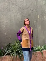 Cárdigan de lana color beige con mangas moradas, puños y ruedo en azul marino, cierre con botones marrones y bolsillos frontales de gamuza.