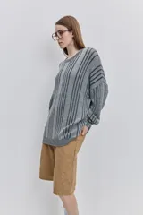 Sweater de punto color gris con diseño de rayas verticales oscuras, cuello redondo y calce relajado de mangas largas.