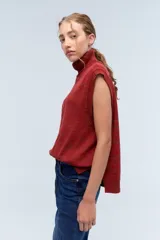 Chaleco de punto azul con cuello alto y diseño de trenzas.