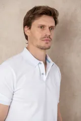 Remera azul marino de piqué de algodón, corte clásico, cuello polo con dos botones y logo de ave bordado en celeste en el pecho.