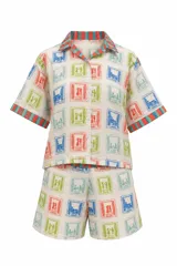 Pijama de algodón de la marca Mutma, compuesto por una camisa de manga corta con solapas a rayas y short a juego, con estampado de estampillas de colores. Incluye un necesaire acolchado con el mismo estampado a rayas en tonos naranja y celeste.