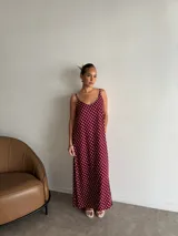 Vestido largo de crepe con estampado de lunares negros sobre fondo blanco. Presenta un diseño de corte holgado con breteles finos y escote redondeado.