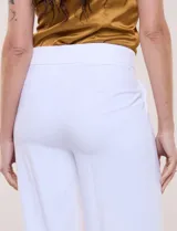 Pantalón sastrero blanco de tiro alto, corte wide leg y pierna ancha con caída fluida. Cuenta con cintura ancha lisa, cierre frontal oculto y bolsillos laterales.