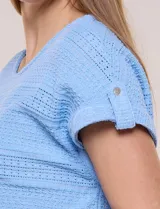 Blusa celeste de tejido pointelle calado, con escote redondo, mangas cortas con dobladillo y presilla con botón, y ruedo curvo.
