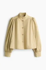Campera corta de sarga color beige, con cuello alto, cierre frontal de botones, mangas largas abullonadas con puños ajustados y bolsillos laterales ribeteados.