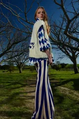 Camisa de corte holgado con cuello solapa y cierre frontal abotonado. Presenta un estampado geométrico de rombos en colores verde y rosado, con un bolsillo frontal en el pecho.