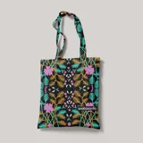 Bolso de mano tipo tote bag negro con estampado de flores y hojas en tonos rosa, verde, marrón y celeste.