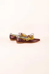 Zapato blucher de cuero con estampado animal print en tonos marrones y dorados, con cordones finos color borgoña y detalle de flor en el extremo del cordón.