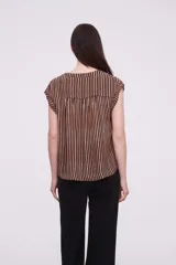 Blusa sin mangas de corte holgado, confeccionada en tela de viscosa con estampado de rayas verticales en tonos mostaza y blanco. Presenta cuello en V profundo y detalles bordados en los hombros.