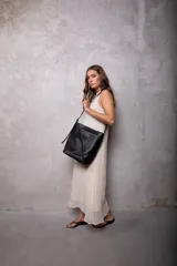 Bolso tipo bucket bag de cuero plena flor negro, con diseño amplio y liviano. Cuenta con cierre metálico, forro de sarga de algodón, bolsillo interior, correa larga ajustable y herrajes metálicos con acabado níquel.