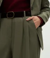 Pantalón de sastrería modelo wide leg color verde militar, confeccionado en crepé. Presenta pliegues delanteros, cintura con trabillas e incluye un cinturón de gamuza a tono.