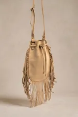 Cartera tipo bucket bag color camel, confeccionada en material sintético con acabado gamuzado. Presenta un diseño decorado con flecos largos en todo el contorno, cierre mediante cordón ajustable y correa larga regulable.