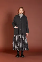 Chaqueta de corte holgado en color gris oscuro con un sutil patrón de cuadros. Posee cuello con solapa, cierre frontal de botones y dos bolsillos delanteros de parche.