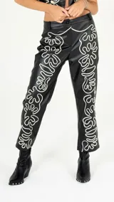 Pantalón negro de cuero sintético con bordado blanco en los laterales.