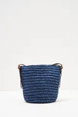 Bolso bandolera azul tejido con bolsillo de cuero marrón en el frente y correa larga de cuero marrón.