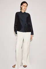 Camisa de estilo oriental confeccionada en mezcla de lyocell con acabado satinado. Presenta cuello redondo, manga larga con puños rectos, bolsillos de plastrón y cierre frontal mediante alamares.