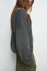 Jersey de punto liso color rojo, con escote en V profundo y mangas largas. Presenta terminaciones en rib en el cuello, puños y ruedo.