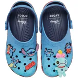 Zuecos Crocs Classic Clog inspirados en Disney Lilo & Stitch, de color celeste en la parte superior con estampado de Stitch y adornos Jibbitz exclusivos, y suela roja con estampado de hojas tropicales.