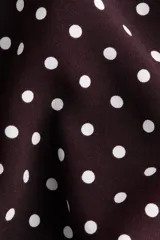Vestido midi bordó con estampado de lunares blancos, cuello camisero, botonadura frontal y mangas cortas raglán. Cuenta con elástico en la parte posterior de la cintura y cinturón extraíble para atar.