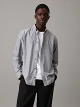 Camisa de vestir gris claro de corte regular, confeccionada en tejido Oxford de algodón y elastano, con cierre frontal abotonado, mangas largas y logo CK bordado en el pecho.