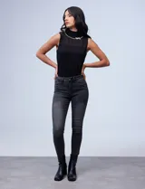 Jean skinny tiro alto de mezclilla negra desgastada, con cinco bolsillos y cierre frontal.