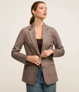 Blazer marrón con estampado de cuadros, confeccionado en punto roma. Tiene solapa en el cuello, cierre con un botón, bolsillos delanteros y corte entallado.