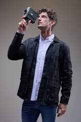 Campera tipo camisa de cuero negro con cuello clásico, cierre frontal con botones, bolsillos de parche en el pecho y corte recto.