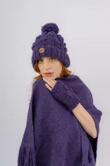 Ruana artesanal tejida en telar manual, color violeta, con textura rústica y terminaciones con flecos en los bordes. Incluye etiqueta de cuero con la marca Pura Lana.