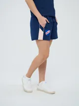 Bermuda deportiva azul marino Umbro del Club Nacional de Football, con bolsillos laterales, cordón ajustable en la cintura y detalles con líneas laterales. Incluye el escudo del club y el logo de la marca bordados.