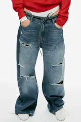 Jeans de tiro medio y corte baggy con cinco bolsillos, trabillas y rotos decorativos. Cuenta con detalle de cinturón confeccionado en el mismo tejido y cierre frontal con cremallera y botón metálico.