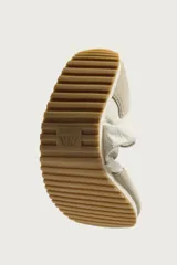 Zapatilla deportiva estilo barefoot, color marrón, con diseño de paneles en combinación de materiales y detalles en serraje. Cuenta con puntera redondeada y ancha, cordones en color crema y suela fina de goma flexible en contraste.