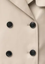 Abrigo corto tipo chaqueta de cuero ovino color beige, con diseño de doble botonadura, solapas con muesca y manga larga.