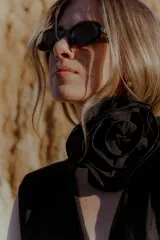 Mono largo color marrón chocolate, con escote en V, sin mangas, con hombreras y bolsillos laterales. Incluye accesorio tipo flor para usar como cinturón o collar.