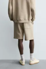 Bermuda de algodón color beige, estilo jogger, con corte relajado, cintura elástica ajustable con cordón y bolsillos laterales y trasero.