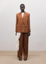 Blazer de corte sastrero color tostado, con diseño de doble botonadura, solapas clásicas y bolsillos laterales con solapa.