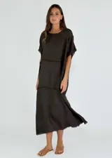 Vestido midi de lino color negro, con corte holgado, cuello redondo y detalles de costuras horizontales con bordes desflecados.