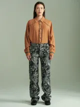 Pantalón tiro medio-alto de algodón con apariencia tipo jean, diseño de corte recto y estampado abstracto en tonos oscuros y grises, con bolsillos delanteros y traseros.