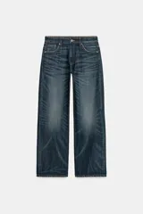 Jeans de tiro medio con corte relajado y diseño de cinco bolsillos. Presenta trabillas en la cintura, cierre frontal con cremallera y botón metálico, con un acabado de lavado desgastado.