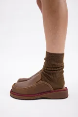 Zuecos de cuero vacuno en color beige, con diseño de punta redondeada y suela plana de goma.