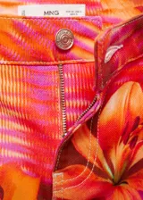 Pantalón de jean estilo wide leg con tiro medio, cierre de cremallera y botón. Presenta un diseño estampado con rayas horizontales y flores, confeccionado en tejido de algodón.