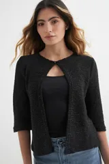 Cardigan verde esmeralda de tejido de punto calado, con mangas 3/4 y corte evasé. Presenta cuello redondo con abertura en forma de gota y cierre con un único botón.