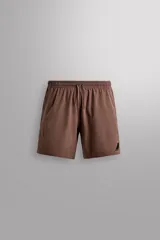 Short deportivo Zara Athleticz color marrón, confeccionado en tejido técnico ligero y elástico con forro interior. Cuenta con cintura elástica ajustable con cordón, bolsillos frontales y aberturas laterales en el bajo.